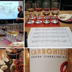 Tasting room with glasses in foreground, wine educator Matt with a presentation i nthe background. A tasting sheet, filled tasting glasses, cheese and charcuterie and cheese plates and a label of a sparkling wien bottle.
