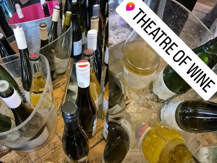 Open bottles of white and sparkling wine in wine coolers filled wth ice.